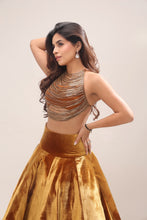Load image into Gallery viewer, A woman modeling a sleeveless metallic bronze crop top and a matching gold velvet flared skirt against a plain light beige studio background.