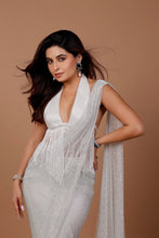 Load image into Gallery viewer, A woman modeling a white sleeveless fringed dress with a draped shawl, posed against a solid warm brown studio background.